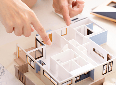 建築模型の間取りを指差しながら打ち合わせする様子